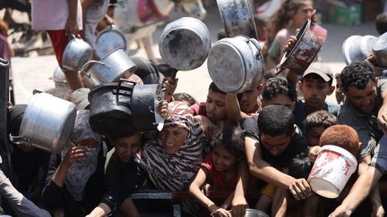 Des Palestiniens lors d'une distribution de nourriture, dans la bande de Gaza, le 28 août 2025, où l'ONU a officiellement déclaré l'état de famine. (KHAMES ALREFI / ANADOLU / AFP)
