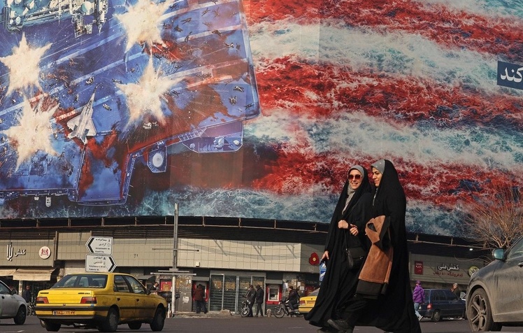 Des femmes iraniennes passent devant un panneau d'affichage anti-américain installé sur un bâtiment de la place Enqelab à Téhéran le 26 janvier 2026. (Photo d'ATTA KENARE/AFP )